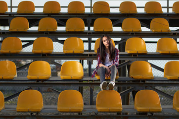 lonely teen girl sitting on tribunes,