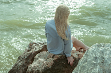 Девушка в рубашке сидит на камнях