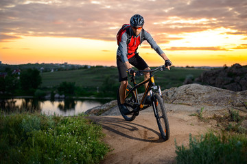 Fototapeta na wymiar Cyclist Riding the Bike on the Mountain Rocky Trail at Sunset