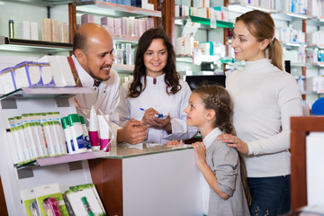 Two pharmacists helping customers