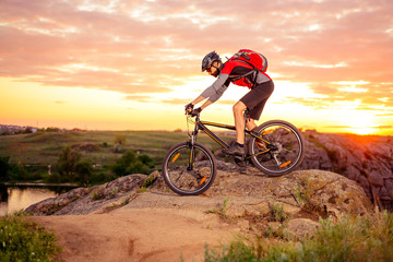 Fototapeta na wymiar Cyclist Riding the Bike on the Mountain Rocky Trail at Sunset