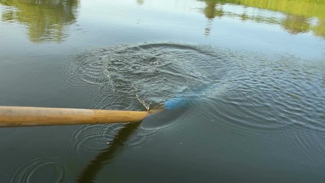 The paddle in the hands of the oarsman. Rowing with an oar in a boat. The flapping motion of the paddle in the water. Active rest at weekends.