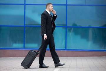 Portrait of happy business man walking with suitcase in a trip.