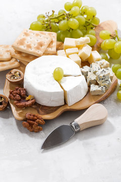camembert, grapes and crackers on a white background, vertical