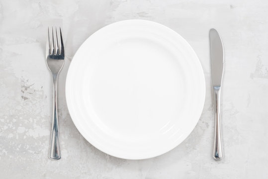 concept photo. White empty plate and cutlery, top view
