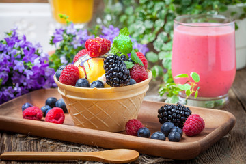 Tasty ice cream dessert with fruit in a waffle bowl.
