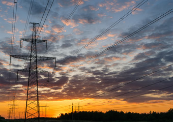 Silhouettes high voltage electric pylon in sunset background