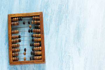 Old wooden scratched vintage decimal abacus on a blue wooden board for the background. Top view. Flat lay.