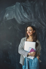 Young beautiful woman with laptop and notes in hands smiling