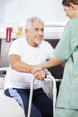 Nurse Assisting Patient To Stand In Rehab Center