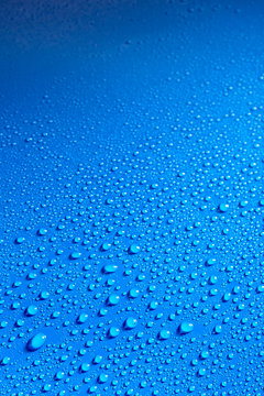 Shiny blue smooth surface covered with dew drops