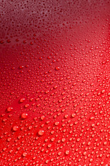 Smooth red surface covered with rain drops