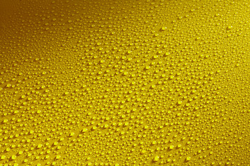 Water drops beading on a yellow metal surface