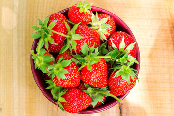 Fresh, organic strawberry in bowl, on wooden table, top view
