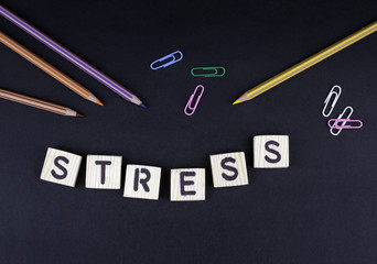 Stress. Text from wooden letters on a black office desk.