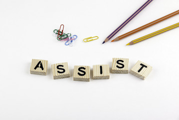 Text: Assist from wooden letterson on white office desk