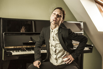 Young woman in men's black suit smoking cigarette sensual near a