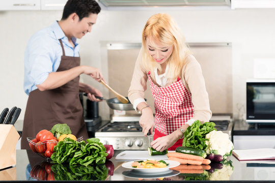 Asian couple cooking in stylish and modern kitchen
