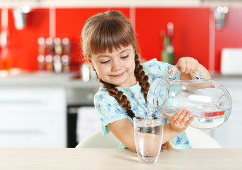 Adorable little girl pouring water in kitchen