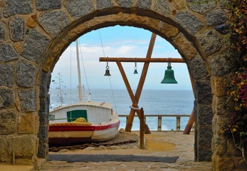 View through and arch onto the ocean outside of Pablo Nerudas house with a wooden construction with...