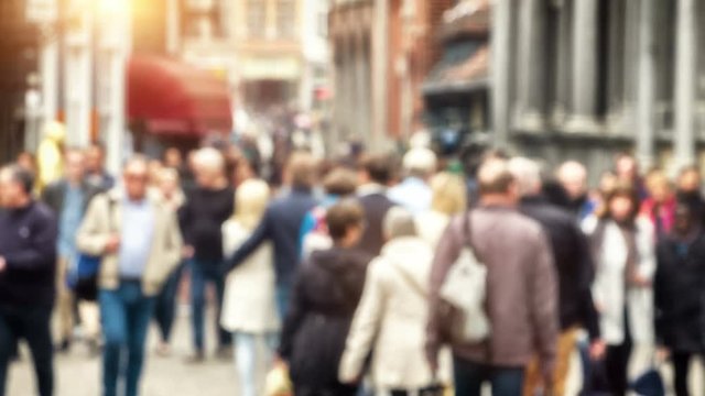 Blurred background with anonymous crowd walking European city street. 4K