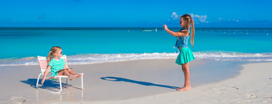 Little girls having fun at tropical beach playing together outdoors