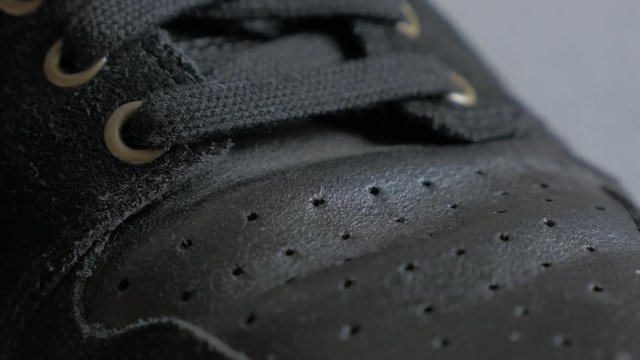 Black leather sneaker snitches and details close-up tilt 4K 2160p UltraHD footage - Slow tilting over leather black sport shoelaces and texture 4K 3840X2160 30fps UHD video