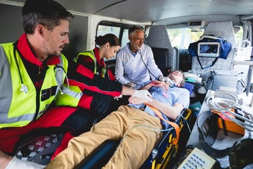 Emergency medical technicians healing injured man in ambulance