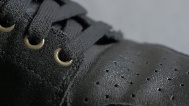 Shallow DOF black leather sneaker snitches and details close-up tilt 4K 2160p UltraHD footage - Slow tilting over leather black sport shoelaces and texture 4K 3840X2160 30fps UHD video