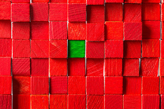 Wand aus roten Holzklötzen, grünes Klötzchen in der Mitte