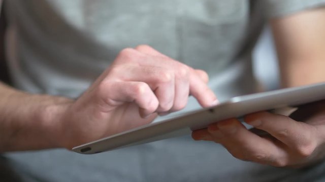 Caucasian young adult making gestures on a tablet ipad device.