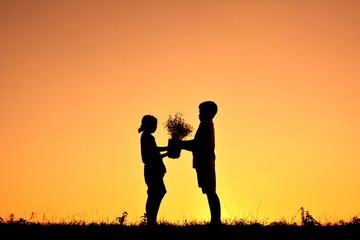 Fototapeta na wymiar Silhouette children holding plant at sky sunset. Concept save world