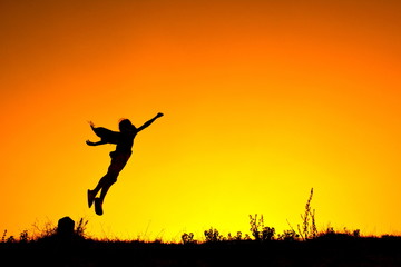 Obraz na płótnie Canvas Silhouette a girl flying at sky sunset