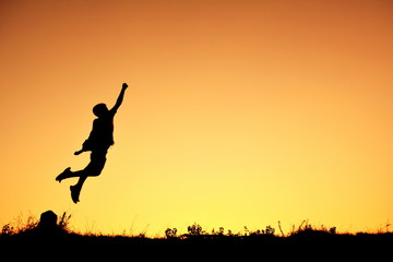 Obraz na płótnie Canvas Silhouette a boy flying at sky sunset