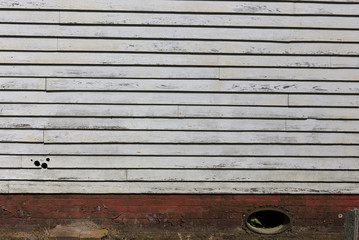 Wall with chalky white chipping paint, wooden siding on an old building