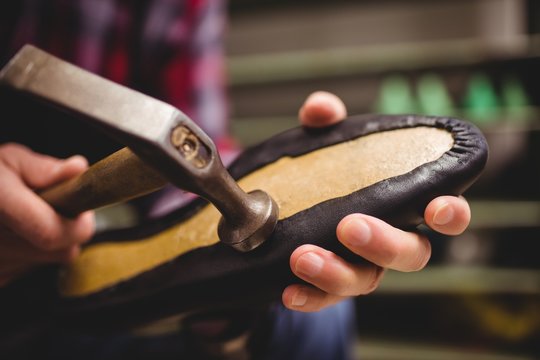 Close up of cobbler making shoes with a hammer