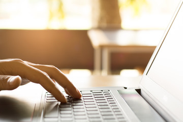 programmer's hand typing with laptop. focus on his finger wih sunlight