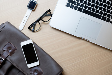 Business workplace from top smart watch, smart phone, glasses, laptop on wooden desk , retro style vintage tone