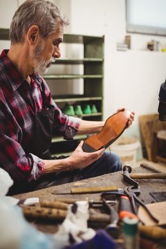Profile view of cobbler looking the sole of a shoe