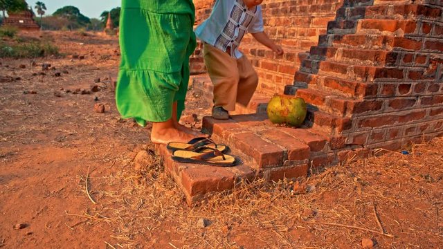 young woman with toddler son removing shoes before entering temple in the ancient Bagan city in Myanmar (formerly Burma)