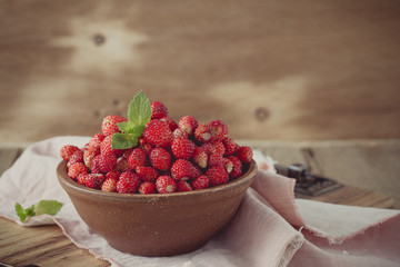 Wild strawberries in ceramic bowl in retro style