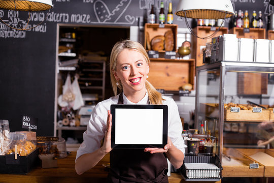 New coffee shop owner standing with blank screen tablet in her hands