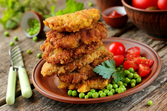 Delicious lunch: pork fried in batter, peas and cherry tomatoes