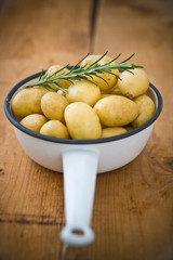Potatoes with rosemary twig in a vintage enamel skillet