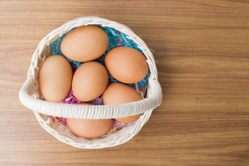 eggs in a basket wooden background, top view