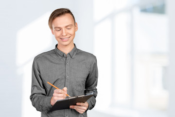 confident young man in shirt making notes in his pad