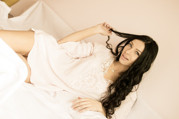 Naklejka premium beautiful playful young lady having fun happy relaxing flirting lying in bed posing on light copy space background portrait