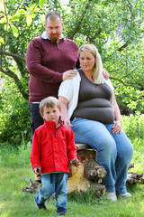 Obraz premium Obese farmer's family together on garden. Pregnant mother and overweight father. People working and enjoying life on countryside. Pregnancy and parenting.
