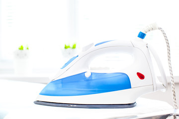 Iron on ironing board on light home interior background