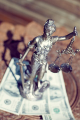sculpture of themis, femida or justice goddess standing on money bribe symbol of corruption